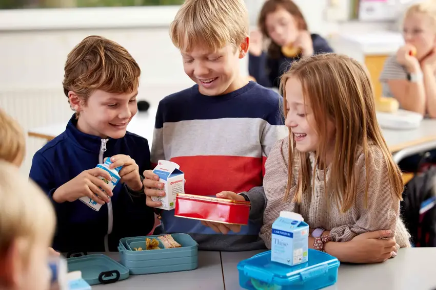 Skolebørn som står med mælkekartoner