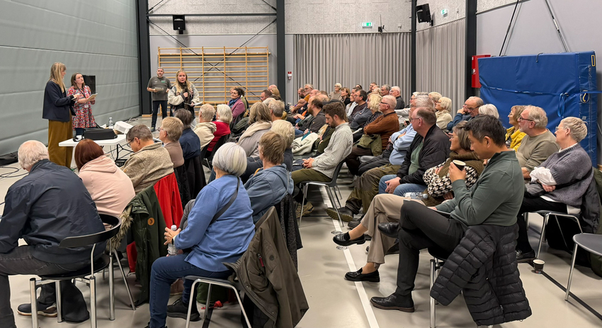 Mange mennesker siddende på stole i idrætshal