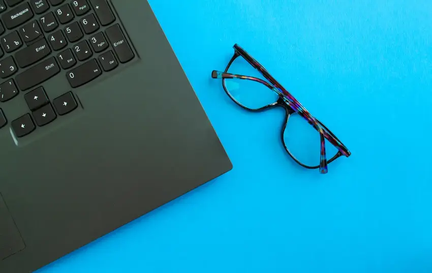 Sort pc keyboard på blå baggrund og et par briller