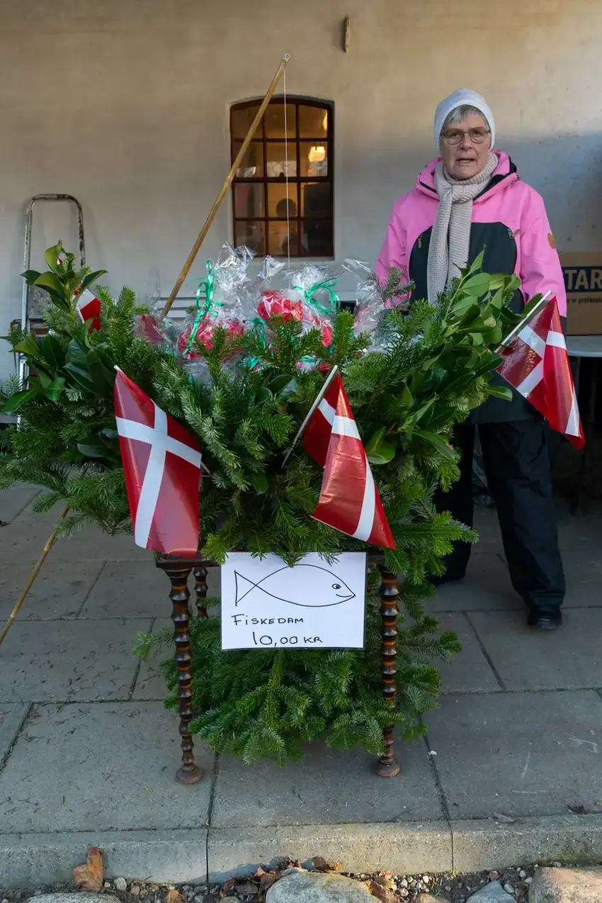 Ældre kvinde står med grangrene og dannebrogsflag
