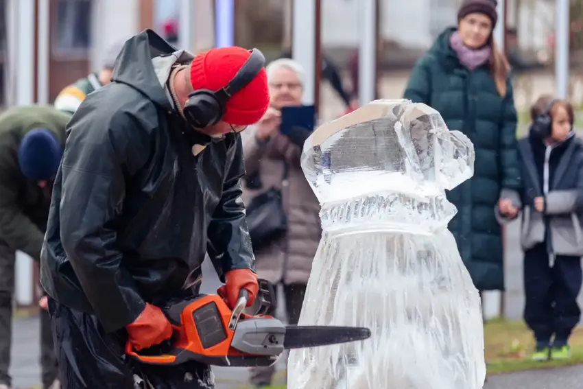 Mand skærer isskulptur med motorsav