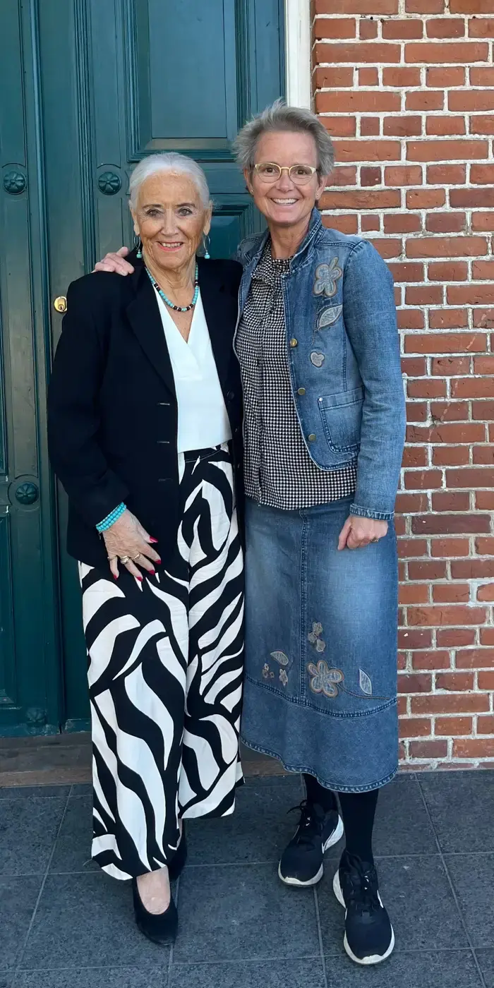 To kvinder står foran en dør og smiler