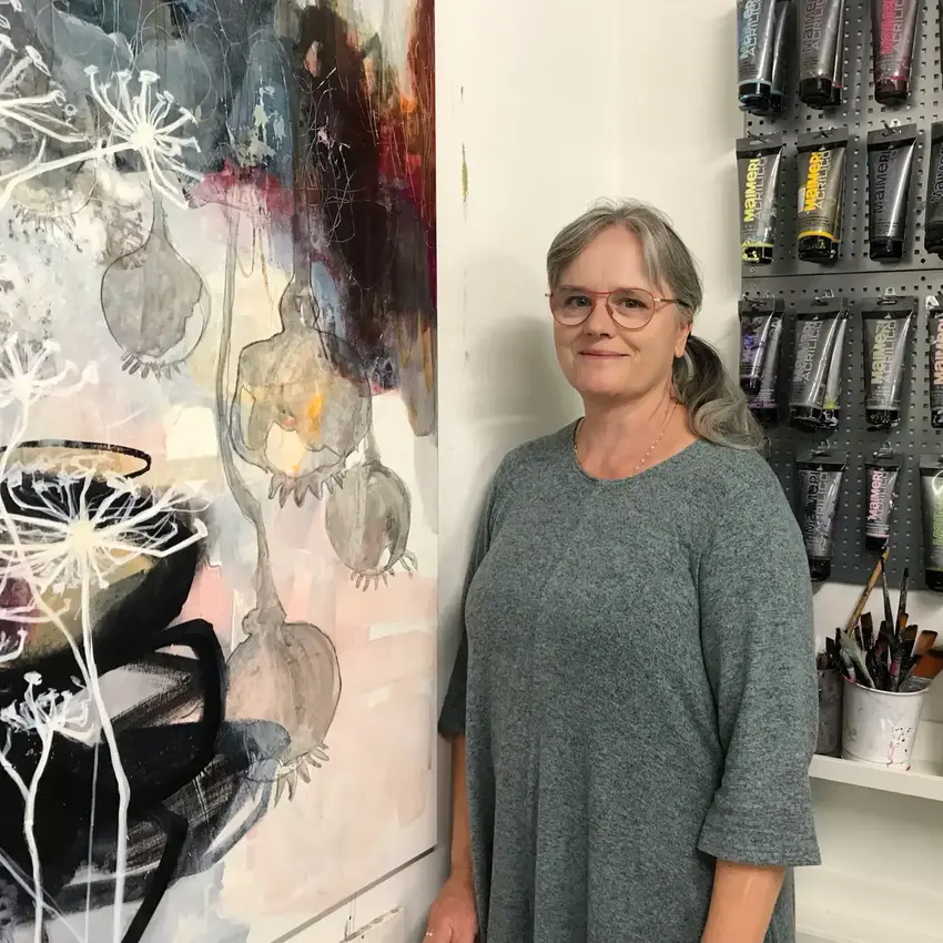 Kvinde med gråt hår står ved maleri