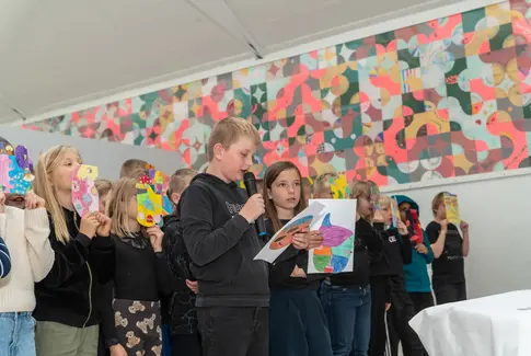 Børn med mikrofon synger i farverigt lokale