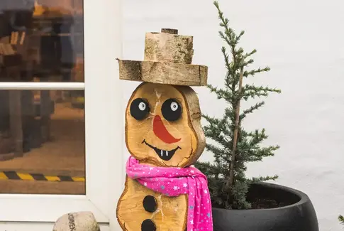 Snemand fremstillet i træ, iført pink halstørklæde