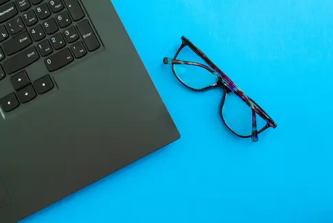 Sort pc keyboard på blå baggrund og et par briller