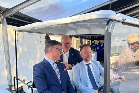 Tre mænd i jakkesæt kører golfvagn