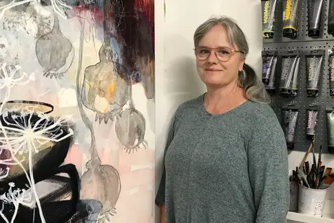 Kvinde med gråt hår står ved maleri